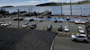 A parking area with vehicles, a dock, and a body of water under a partly cloudy sky.