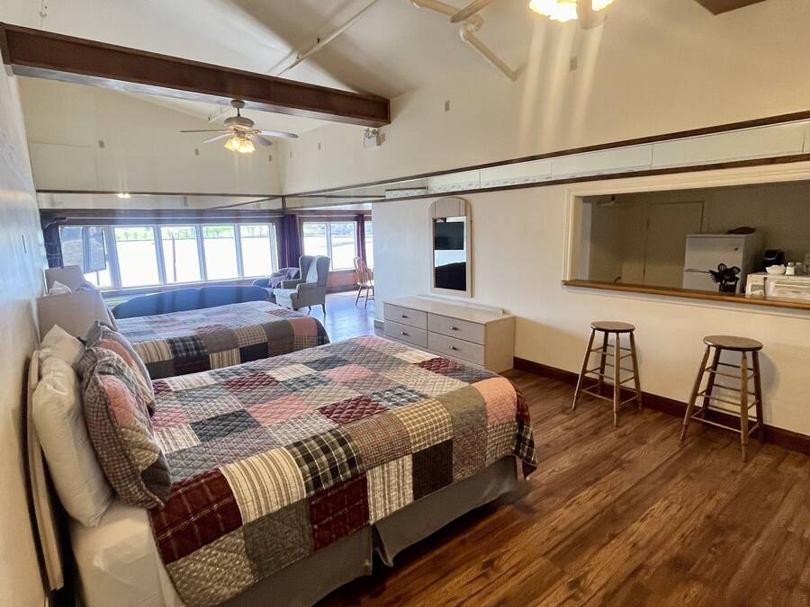 Ruime kamer met een groot bed, een plafondventilator, een kitchenette en uitzicht op de omgeving.