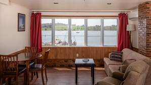 A living room with a large window, wooden furniture, and a brick wall. - The Dockside Inn & Restaurant (Lunenburg)