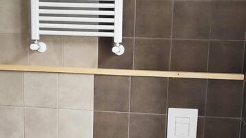 A bathroom with a bidet, toilet, and a towel rack.