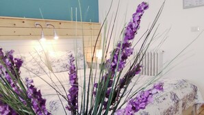 A bedroom with a wooden headboard, a bed with a floral bedspread, and a bedside table with a lamp. - Apulia Bed & Breakfast (Mattinata)