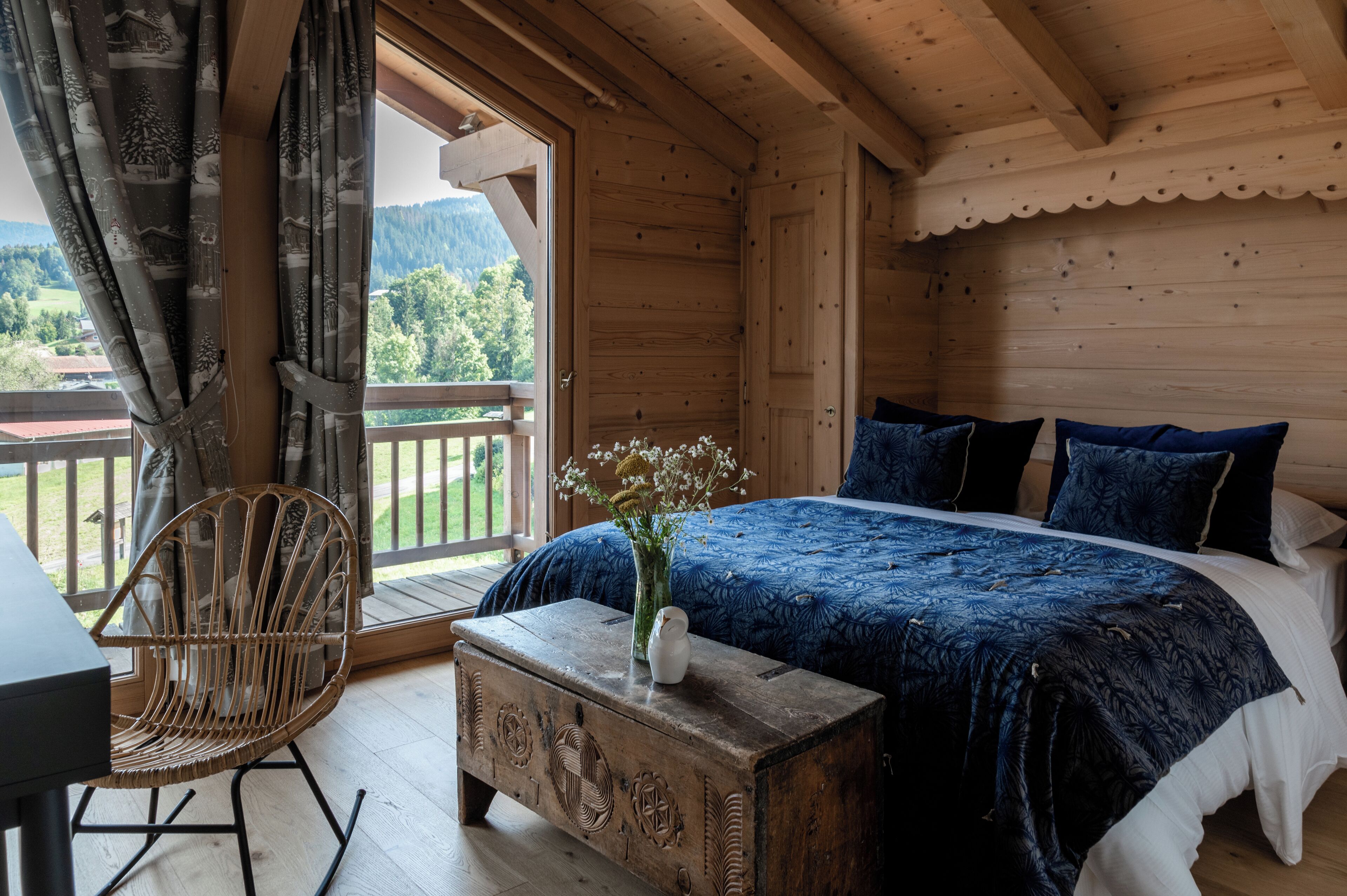 Une chambre dans une cabane en bois, avec un grand lit, une chaise et une petite table.