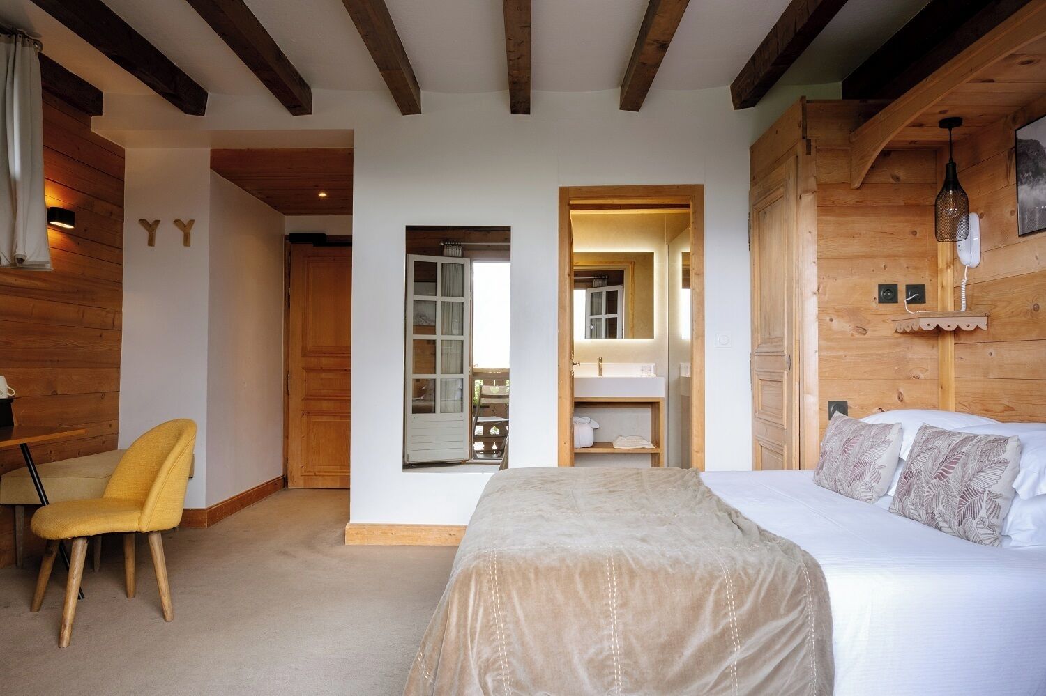 Un dormitorio con cama, una silla, un baño pequeño y paredes de madera.