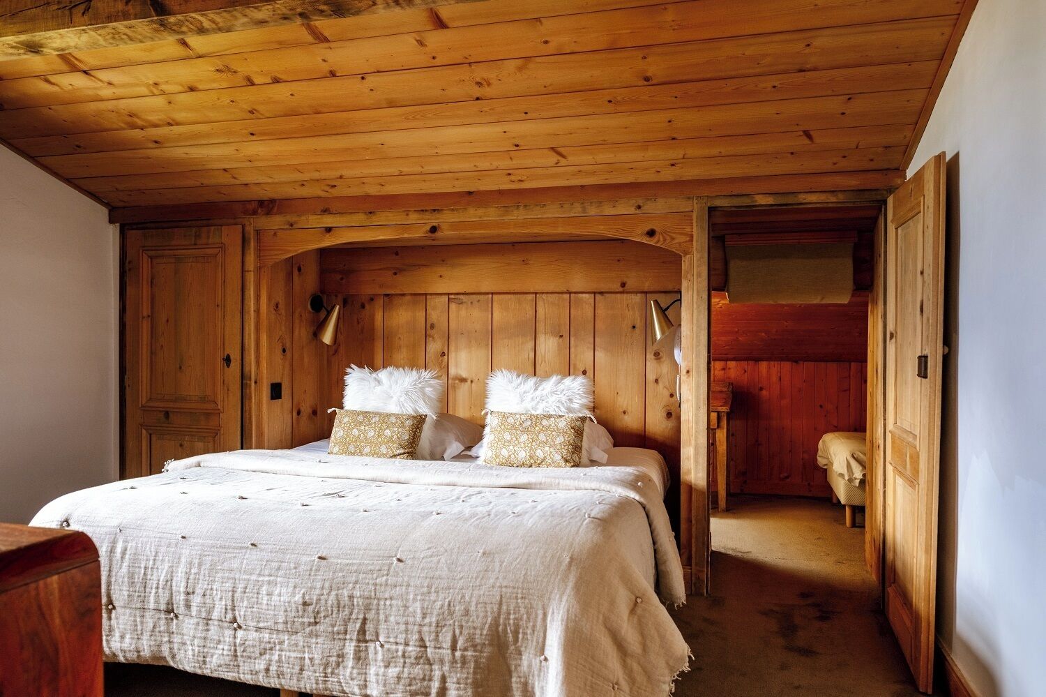 A wooden room with a bed, two pillows, and a nightstand.