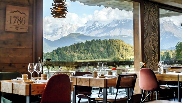 Een restaurant met uitzicht op een berg, een houten interieur en het nummer '1786' op de muur.