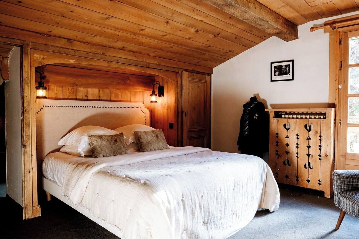 A wooden bedroom with a bed, a wardrobe, and a picture on the wall.