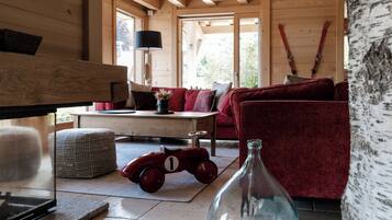 Un interior de madera acogedor con un sofá rojo, un pequeño coche de juguete rojo y una botella de vidrio sobre una mesa.