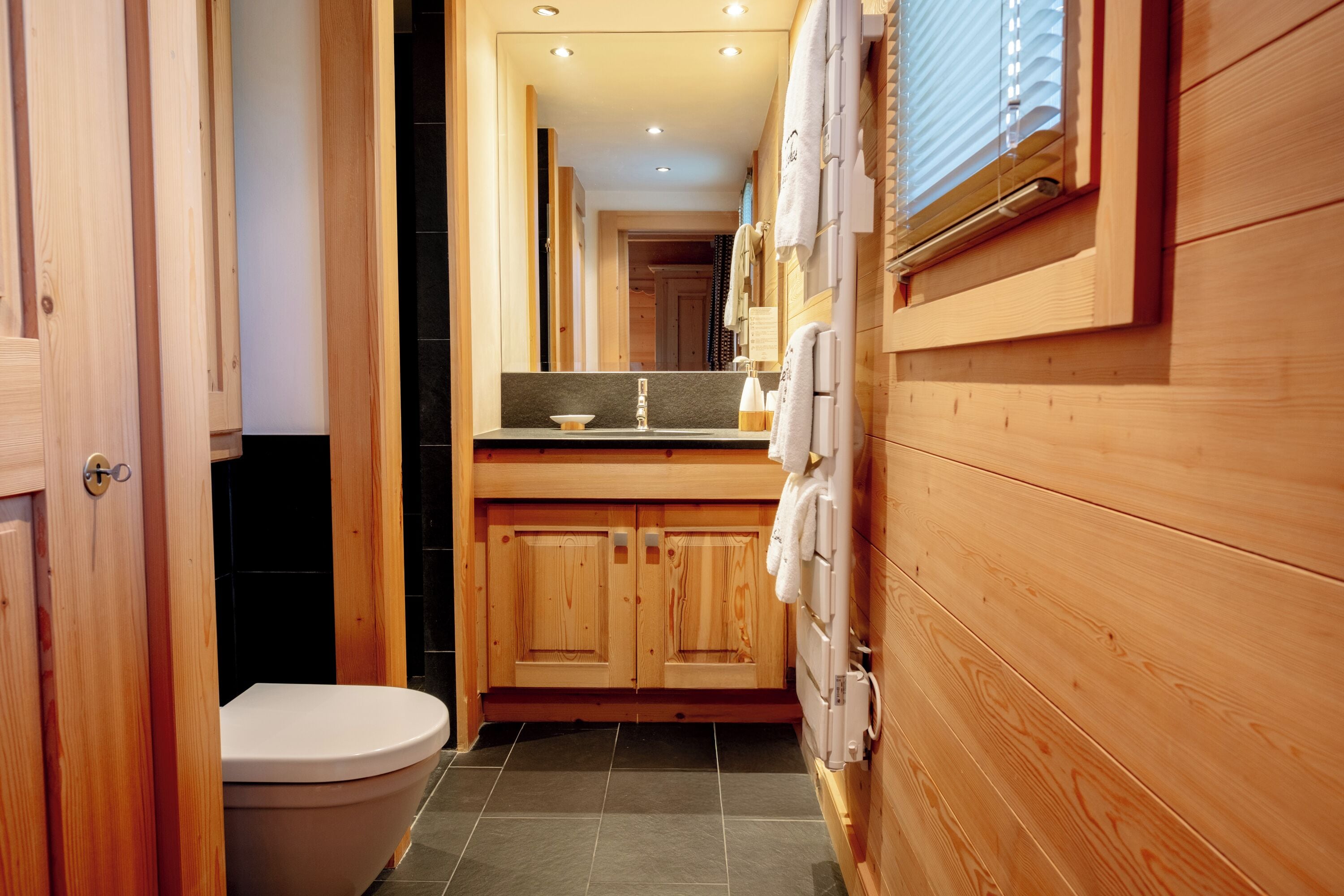 Ein Badezimmer aus Holz mit Toilette, Waschbecken und Handtuchhalter.