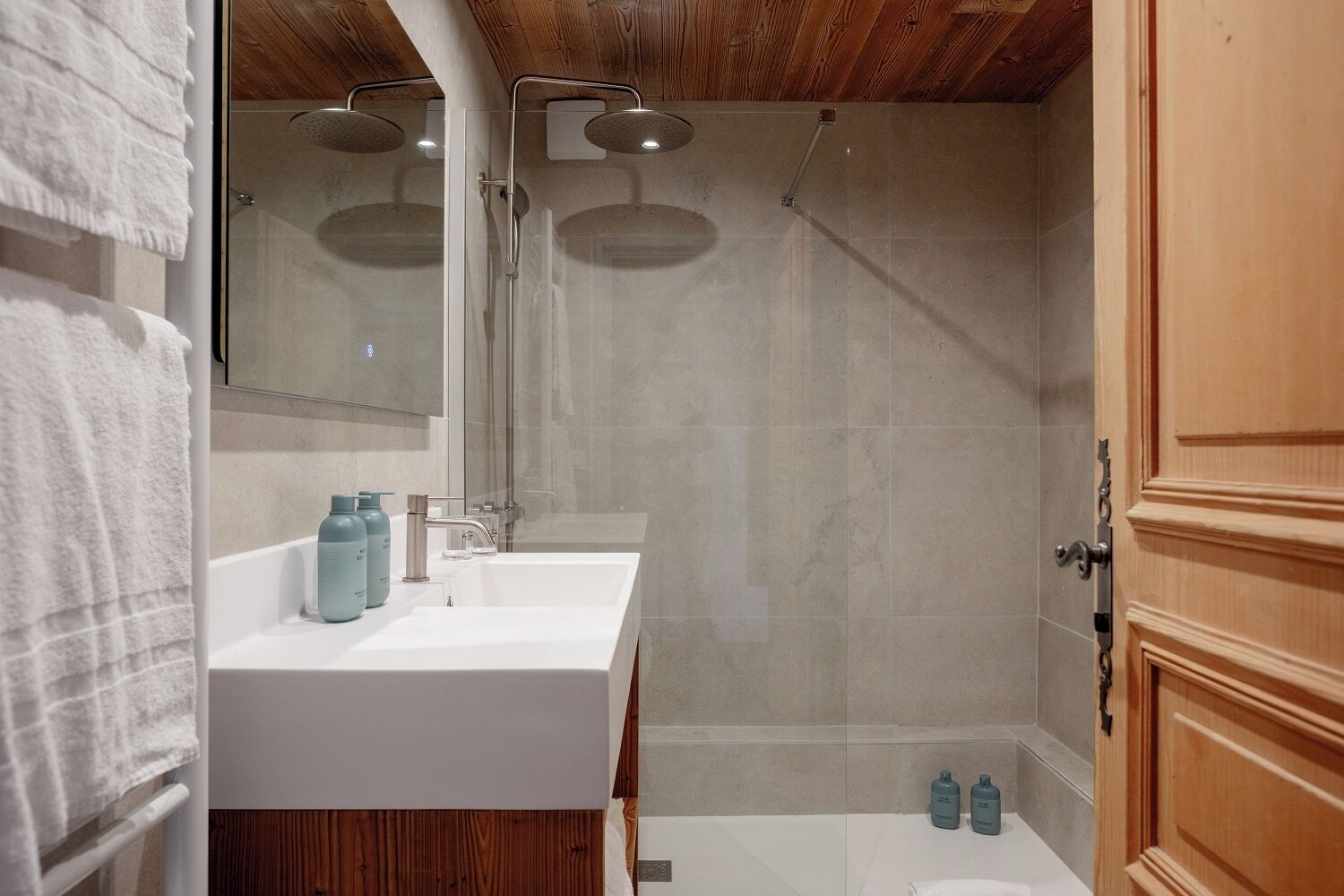 Un baño moderno con dos lavamanos, ducha y un mueble de madera.