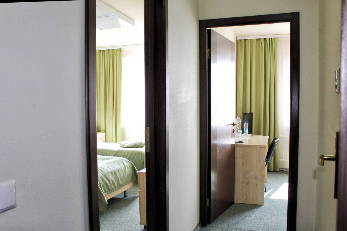 A hotel room with a bed, a desk, and a chair.