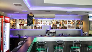 A bar area with a variety of liquor bottles, a Coca-Cola refrigerator, and bar stools. - Sport Time Hotel (Minsk)