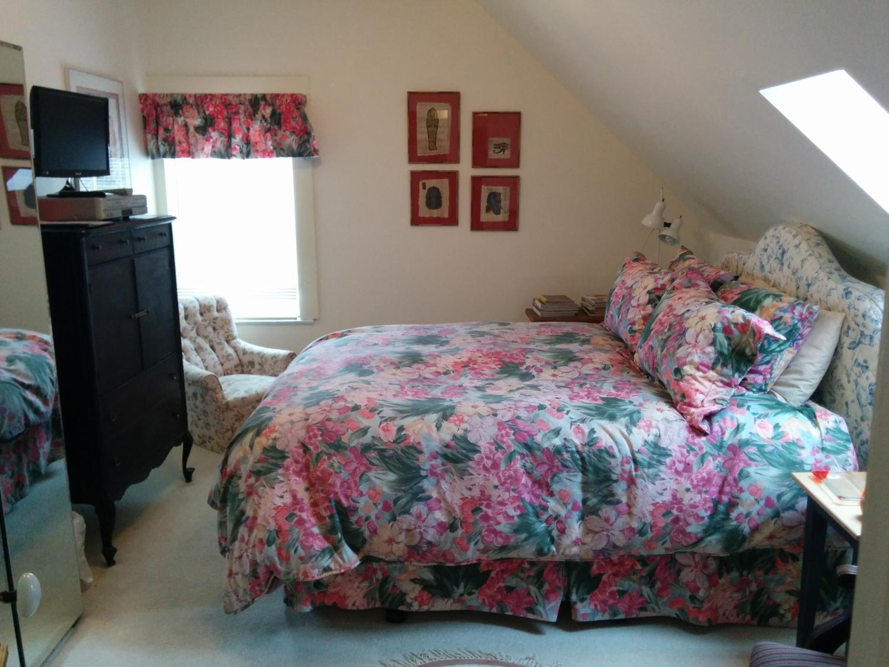 A bedroom with a bed, a dresser, a chair, a desk, and a window.