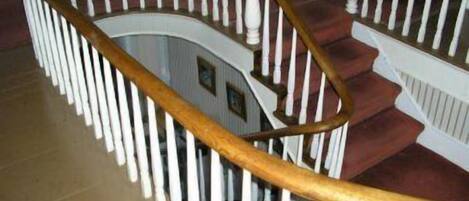 Un escalier en colimaçon avec des balustrades blanches et une main courante en bois.