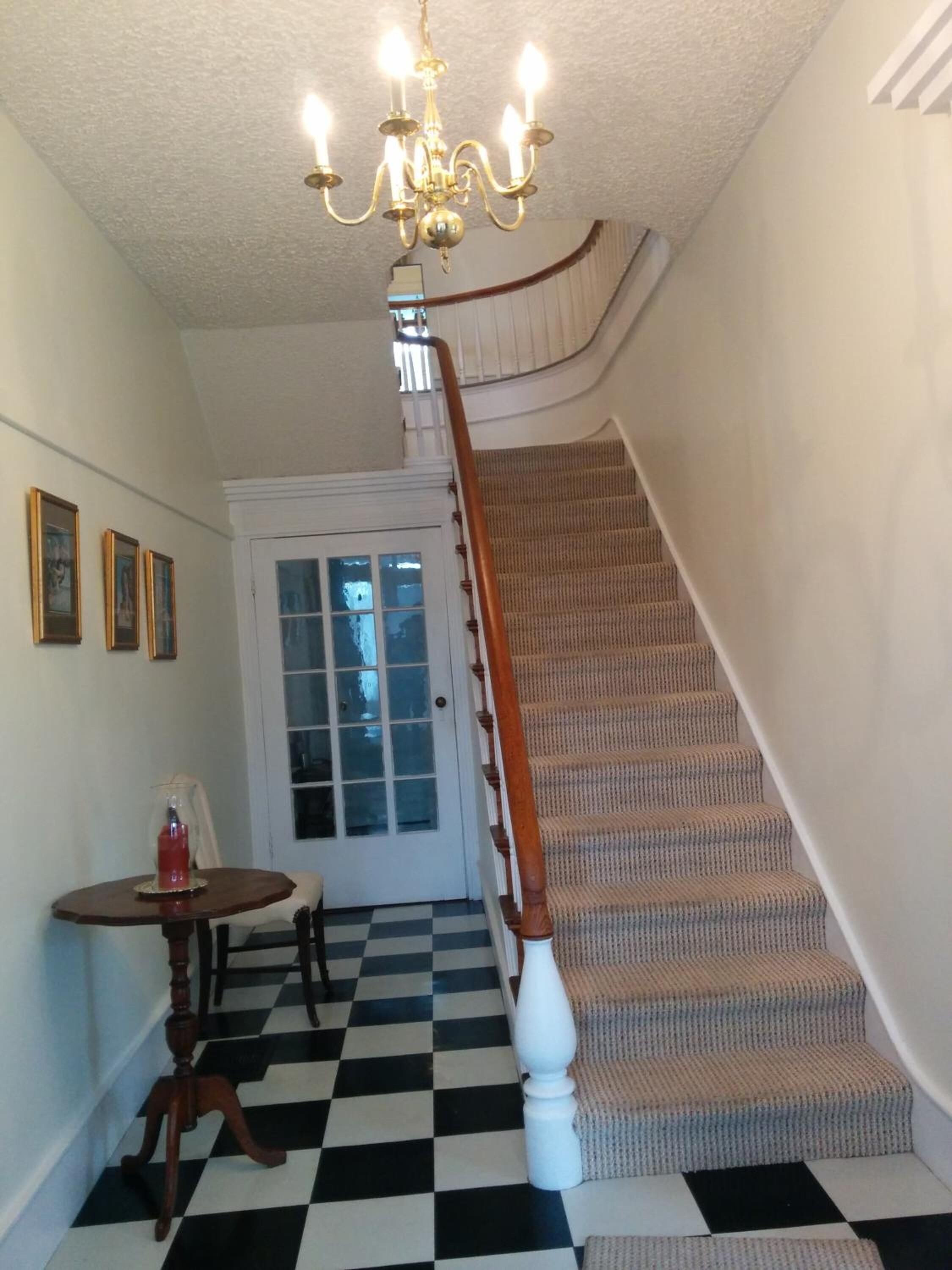 A staircase with a checkered floor leading to a door with frosted glass panels.