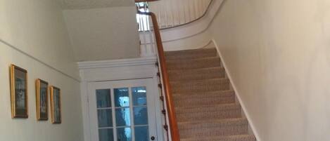 Una escalera con piso a cuadros que conduce a una puerta con paneles de vidrio esmerilado.