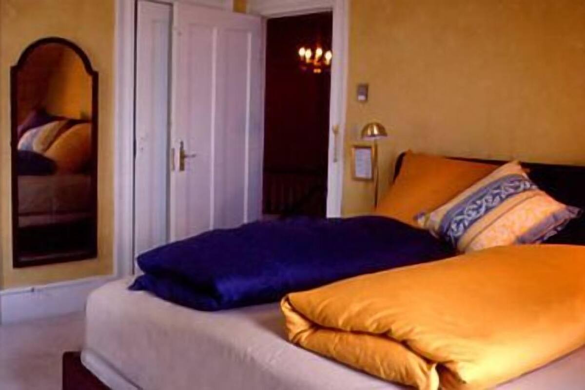 Une chambre à coucher avec un lit, des oreillers, un miroir et une porte.