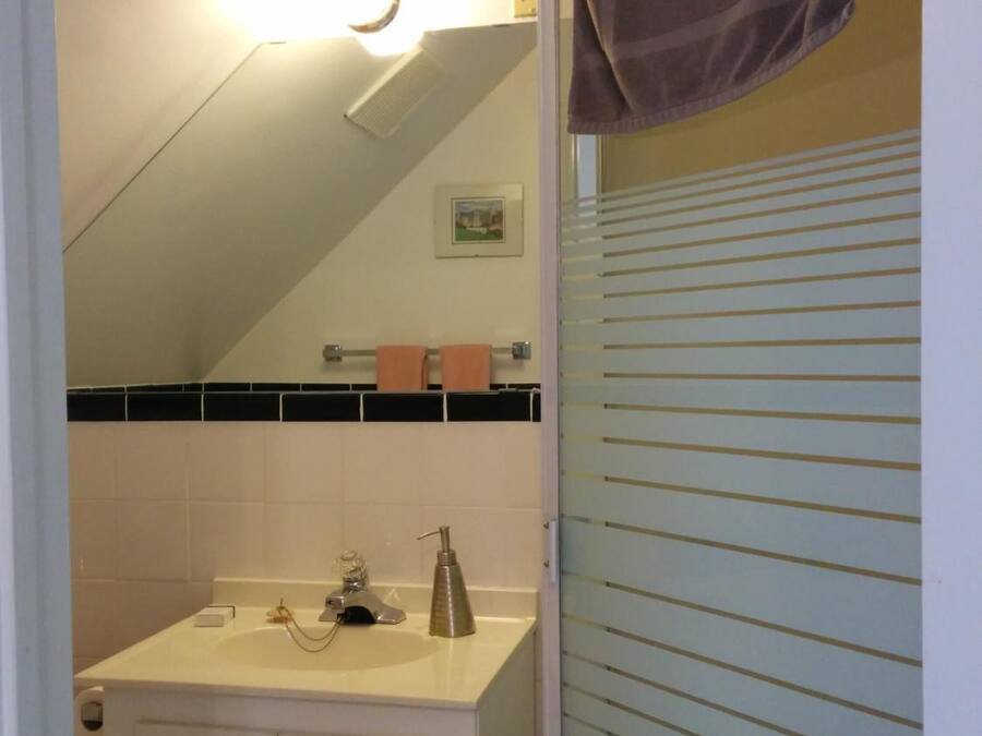 A bathroom with a sink, mirror, towel rack, and a towel hanging on the door.