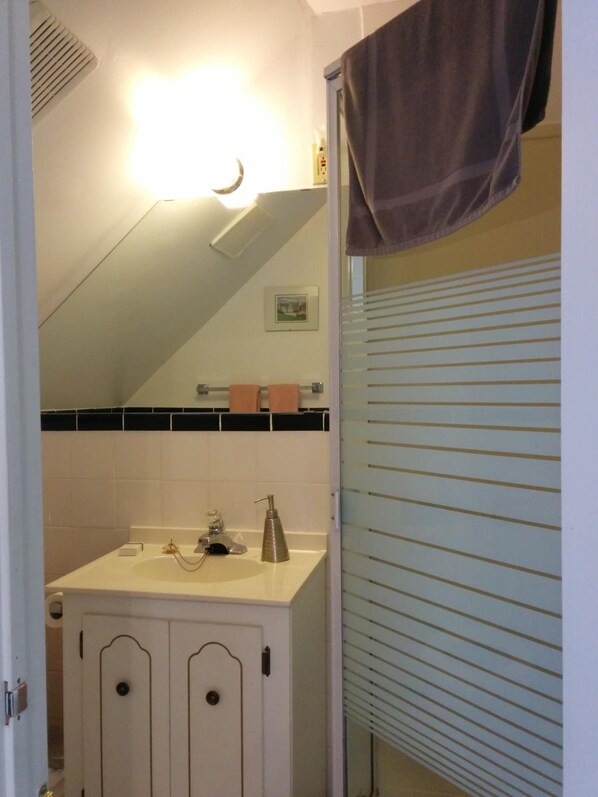 Un baño con lavamanos, espejo, toallero y una toalla colgada en la puerta.