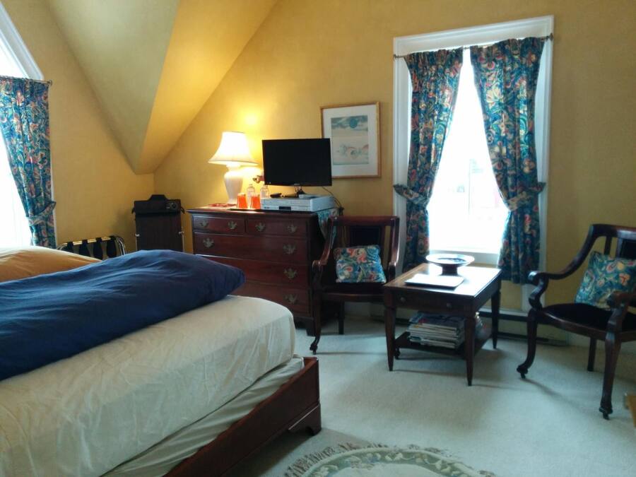 A bedroom with a bed, dresser, desk, chair, and a television.