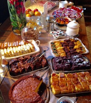 Una mesa de buffet con diversos platos, incluyendo pasteles, tartas y una tarta con una porción faltante.