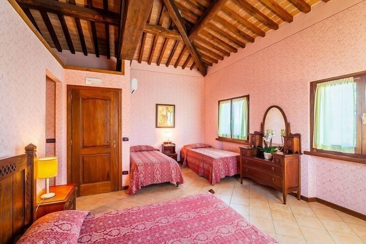 A bedroom with two beds, a wooden dresser, a mirror, and a window with curtains.