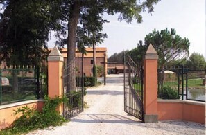 Una entrada con portón y un camino de grava que lleva a un edificio.