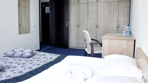 Une chambre d’hôtel avec un lit, une chaise, un bureau et une armoire.
