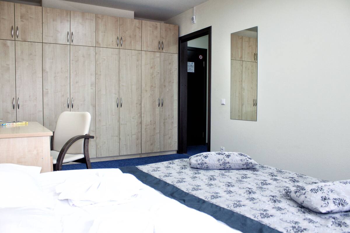 A bedroom with a bed, a chair, a desk, and a wardrobe.