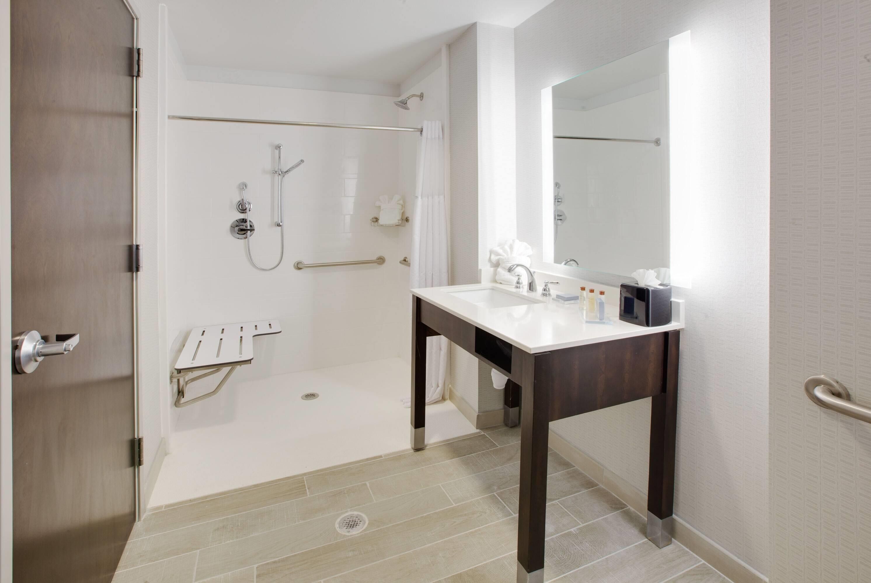 Un bagno moderno con doccia, lavandino e specchio.