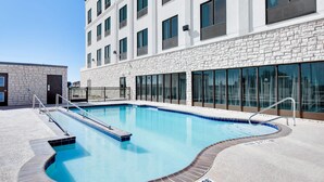 Un edificio moderno con piscina, fachada de piedra y ventanas amplias.