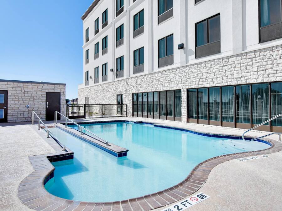 A modern building with a swimming pool, stone facade, and large windows.