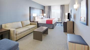 Een hotelkamer met een bed, een bank, een bureau, een stoel en een televisie.