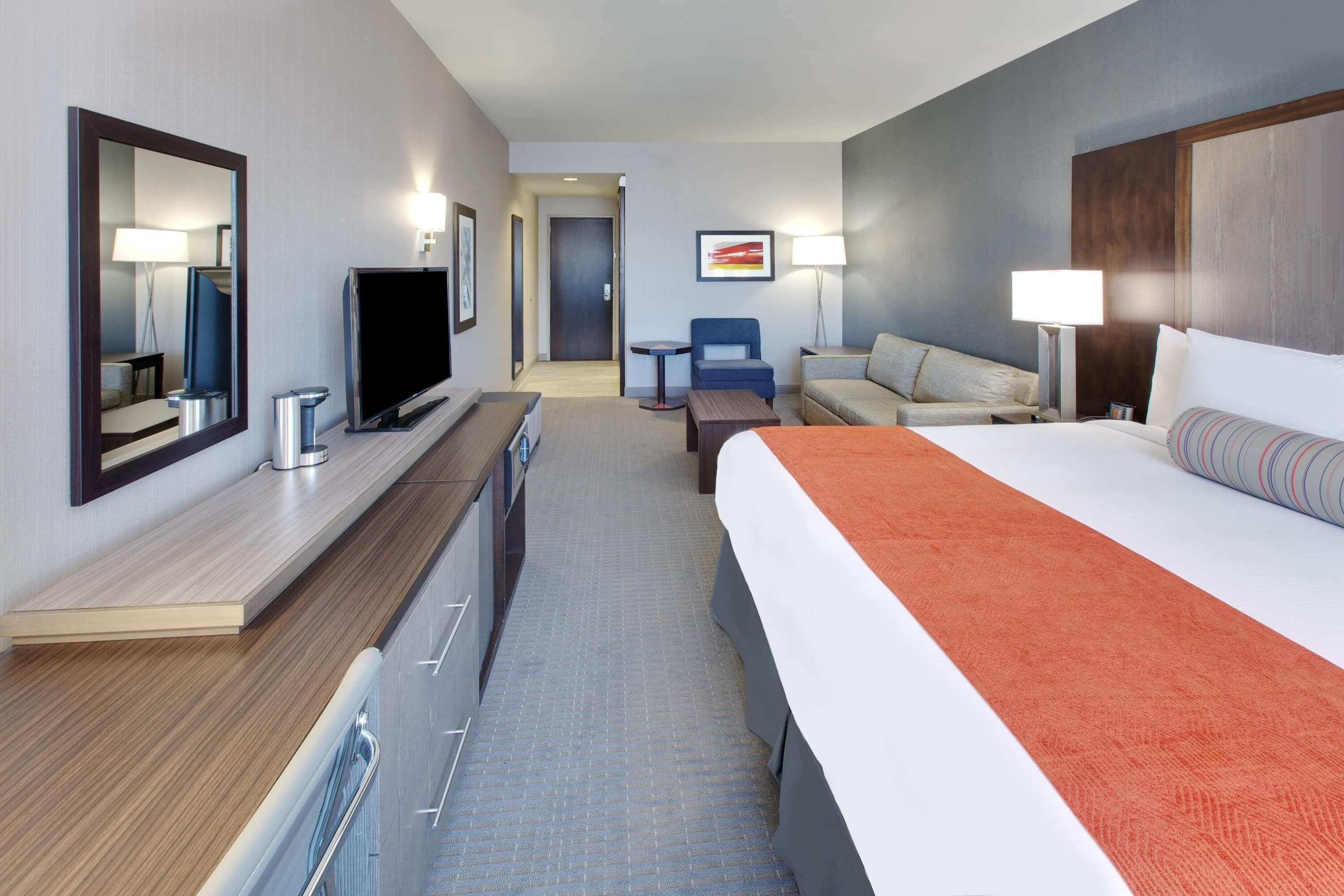 Une chambre d’hôtel équipée d’un lit, d’une télévision, d’un bureau, d’une chaise et d’un canapé.