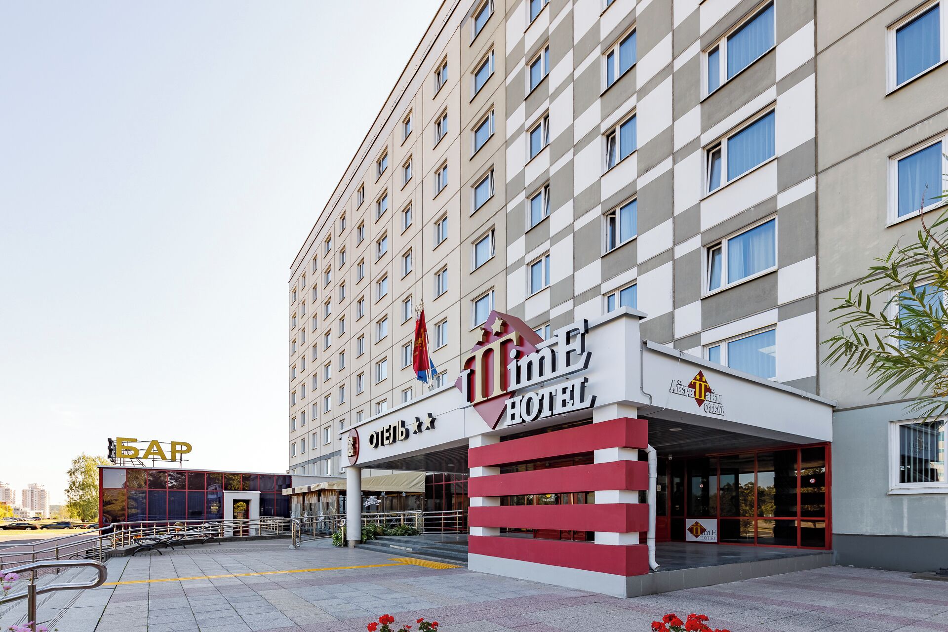 Un hotel con fachada moderna, múltiples ventanas y una entrada destacada con una decoración en rojo y blanco.