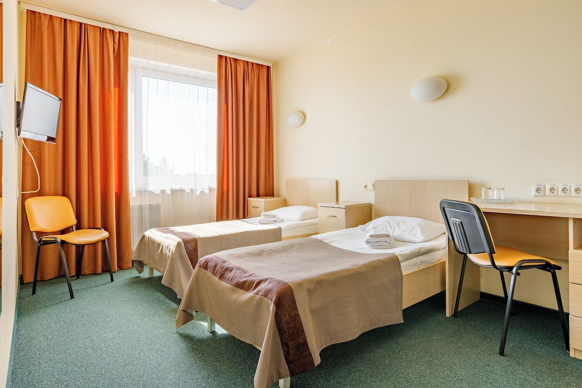 Una habitación de hotel con dos camas, un escritorio, una silla y un televisor.