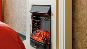 A room with a fireplace, a television mounted above it, and patterned wallpaper.