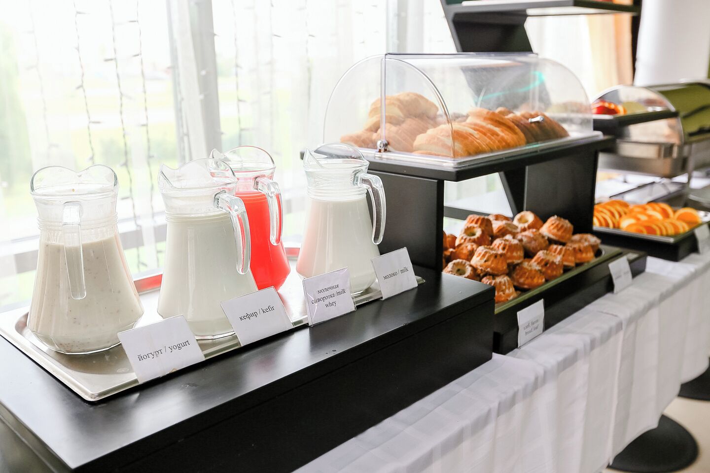 Buffet com bebidas e doces identificados.
