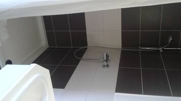 Une salle de bain avec des carreaux noirs et blancs, une baignoire et un espace douche.