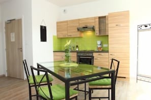 Une cuisine moderne avec des meubles en bois, une table à manger en verre et des chaises vertes.