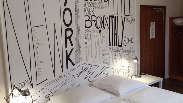A hotel room with a large wall mural featuring city names and landmarks. - Hotel des bois (Seltz)