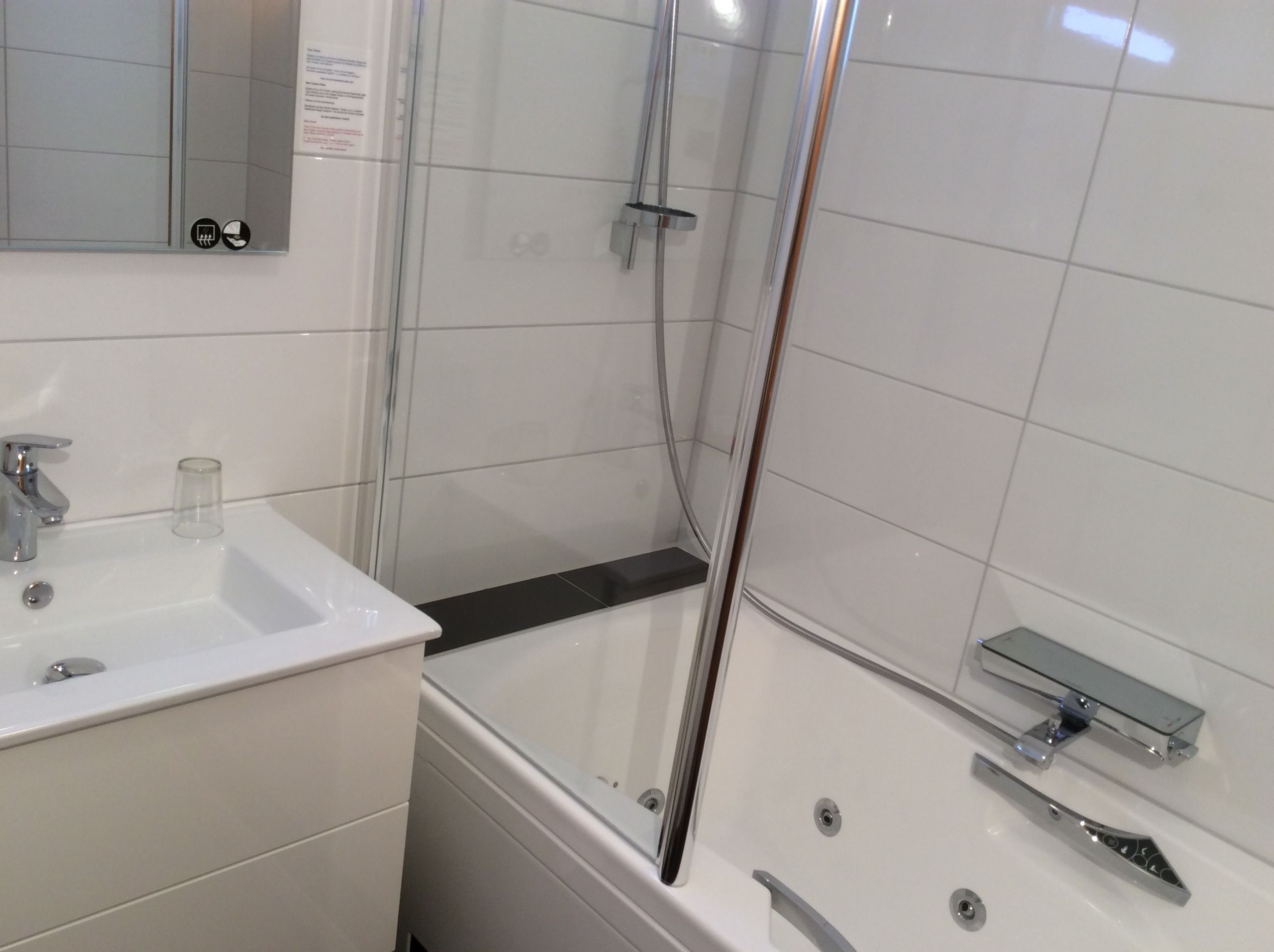 Un baño moderno con cabina de ducha de vidrio, un lavabo blanco y una bañera.
