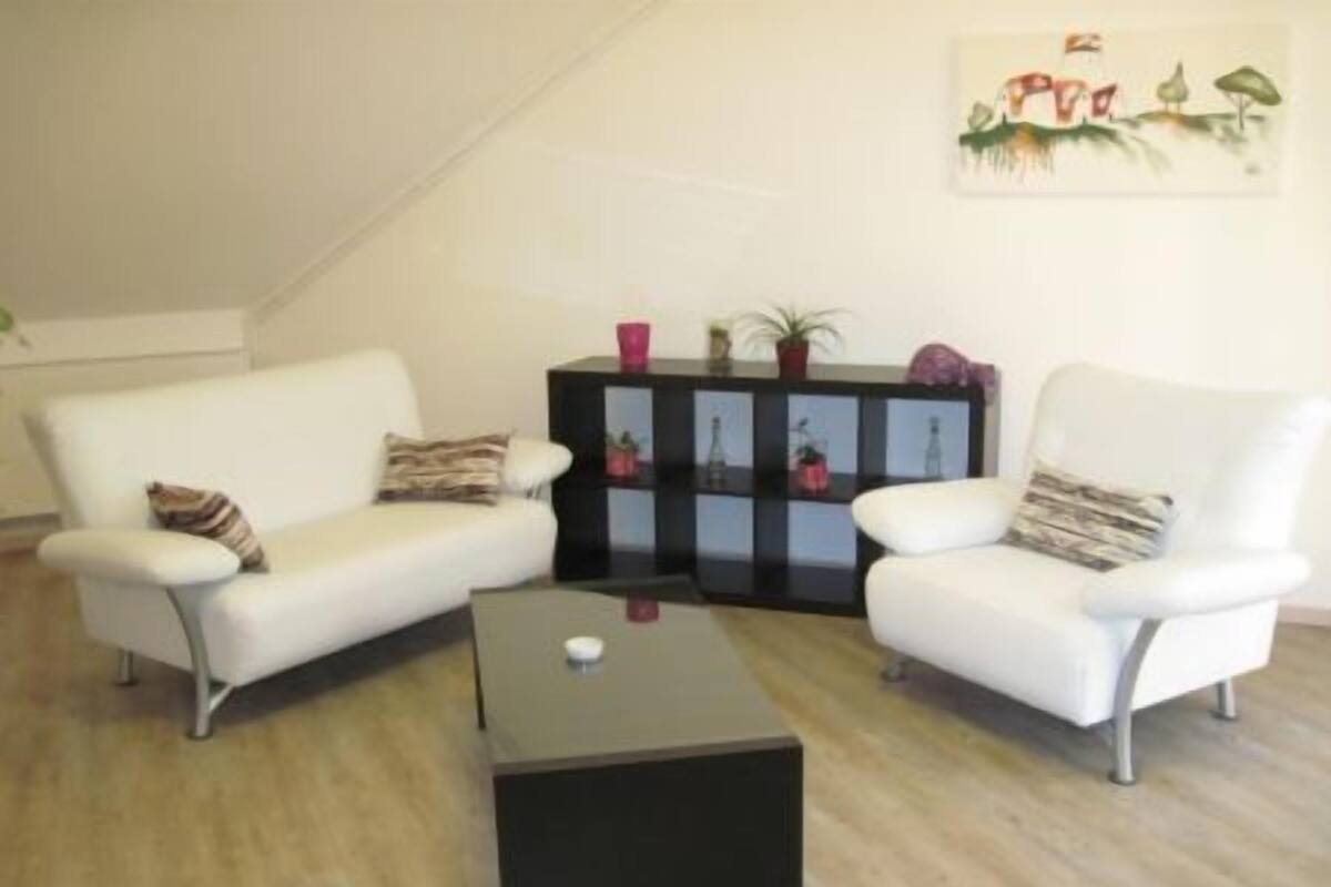 A living room with two white sofas, a black coffee table, and a black sideboard with decorative items.