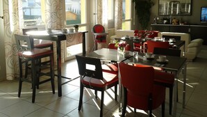 A dining area with a table and chairs, a sofa, and a television in the background. - Hotel des bois (Seltz)