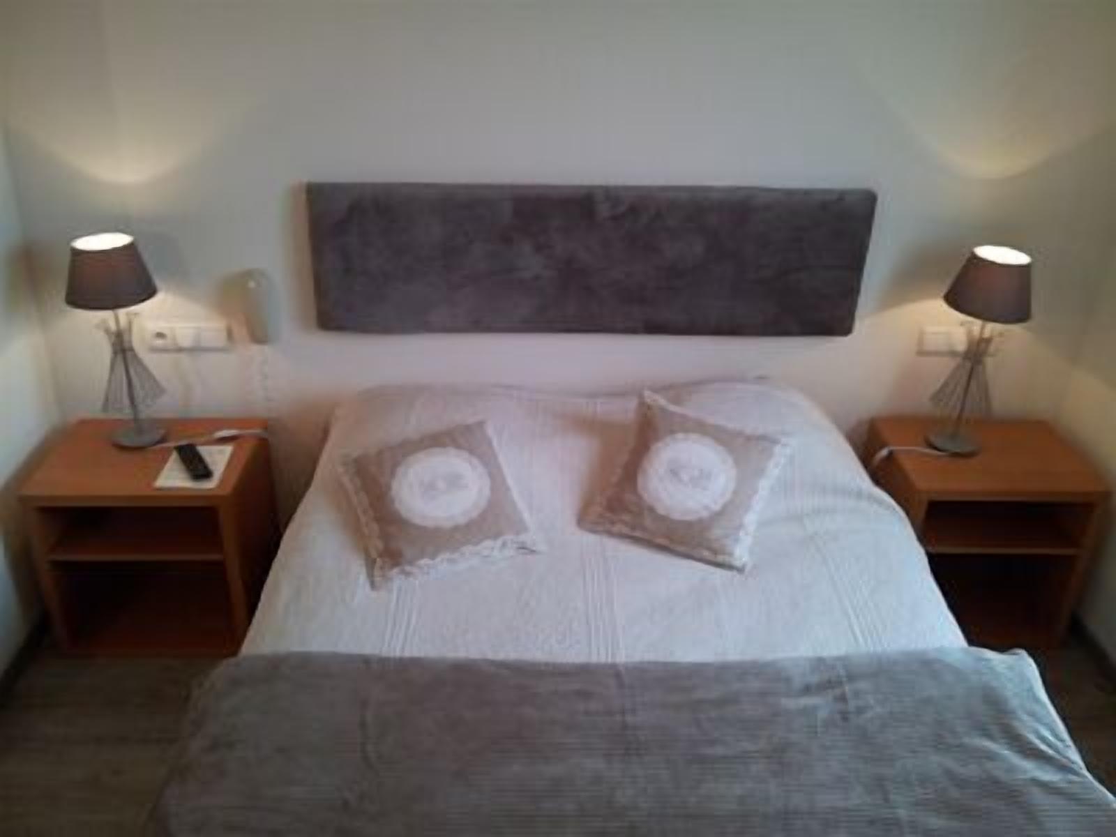 A bedroom with a bed, two nightstands, and two lamps.