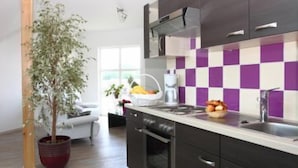 A modern kitchen with dark cabinets, a checkered backsplash, and a potted plant. - Hotel des bois (Seltz)