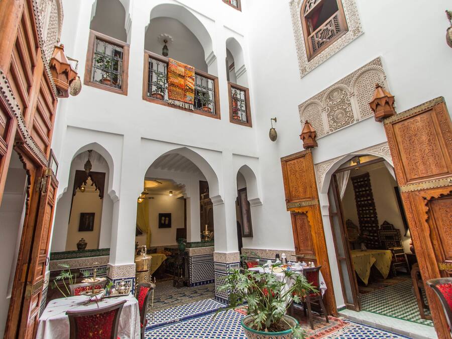 Un patio interior con arcos, un comedor y vista a una habitación con mesa y sillas.