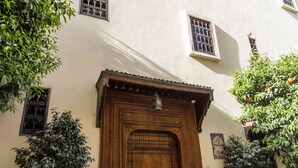 A building with a wooden door, potted plants, and a tiled entrance. - Dar Fes Medina Ziat (Fes)