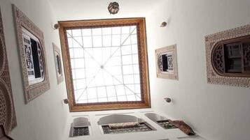 A room with a high ceiling, intricate wall designs, multiple windows, and a skylight.