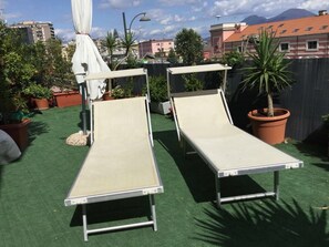 Two metal beds on a rooftop terrace with green artificial turf, surrounded by potted plants and a white umbrella. - Marina ResArt B&B (Naples)