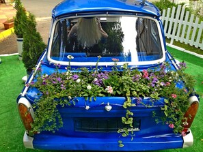 Um carro azul antigo com um arranjo floral na parte de trás.
